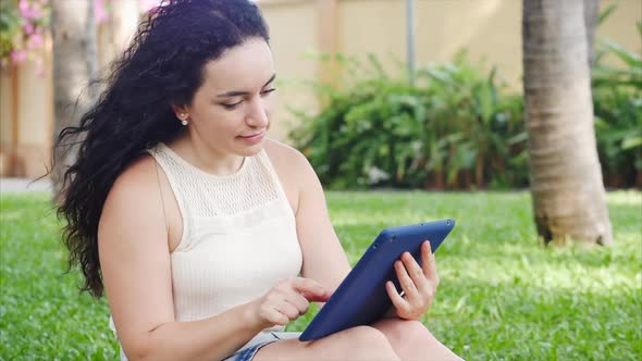 European Woman Makes Use of a Tablet or Phone with a Smartphone, Leafs or Texting with Her Finger