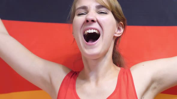 German Young Woman Celebrating while Holding the Flag of Germany