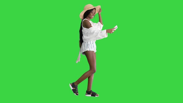 Smiling African American Woman in a Straw Hat Taking Selfie While Walking on a Green Screen, Chroma