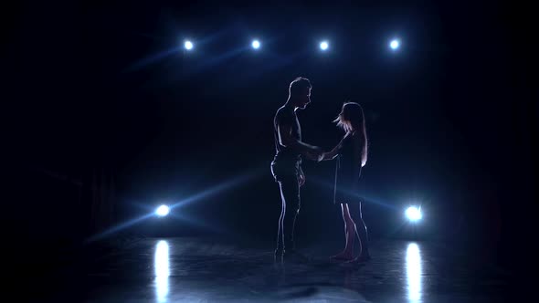 Young Couple Dancing Contemp Against Black Background with Spotlights at Studio.