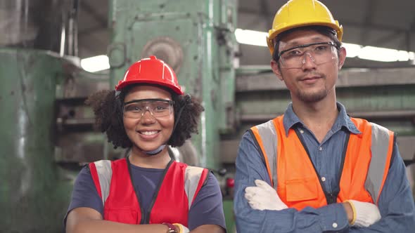 Diverse factory workers in arms crossed smiling to camera in the factory