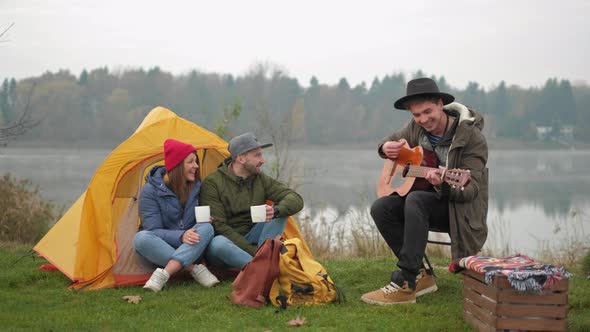 Adventure, Travel, Tourism and People Concept - Group of Smiling Friends with Marshmallow Sitting