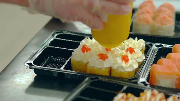 Cook Prepares Japanese Rolls with a Fried Omelet, Adds Red Caviar Salmon.