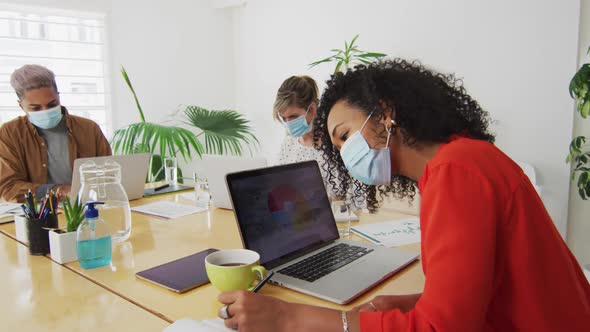 Woman wearing face mask taking notes in office