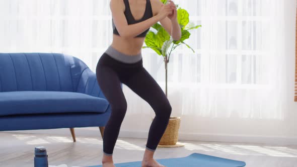 Athletic Healthy Asian young woman in sportswear workout squat excercise at home in bedroom