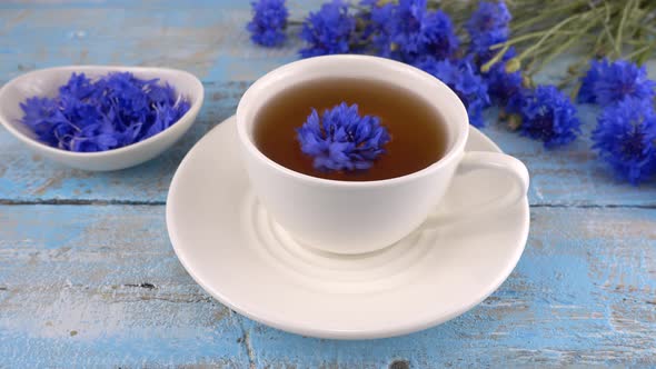 Brewing a tisanes from knapweeds flowers in white cup.