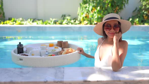 Woman with floating breakfast in pool