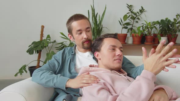 Two Lgbt Men are Sitting Together on the Sofa in the Living Room Talking and Holding Hands