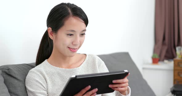 Woman reading on tablet computer at home