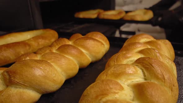 Baker takes bread out into oven with shovel.