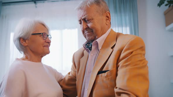 Happy Elderly Couple Dancing at Home in Formal Wear