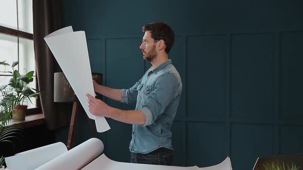 Close Up Shot of Young Man Hands Engineer Opening the Paper and Checking the Construction Drawings