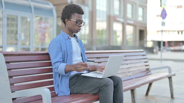 Excited Young African Man Shopping Online with Laptop Outdoor