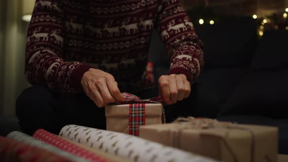 Young adult man packing Christmas gifts. Shot with RED helium camera in 8K