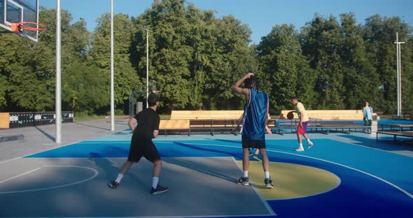 Basketball Players Play Fairgame on Blue Court Against Trees