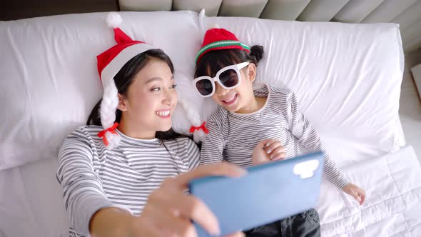 Close up of  young asian mother and her daughter making a selfie or video call.