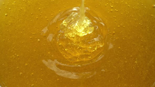 Liquid fresh honey is poured into a plate. Close-up.