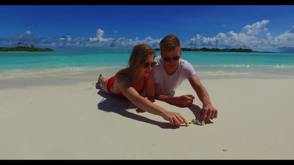 Young couple sunbathe on tropical resort beach time by transparent sea with bright sandy background 