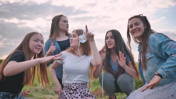 A Group of Girls of Friends are Listening to Music on Headphones and Dancing to a Friend