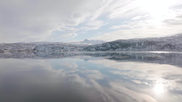 Surface of water in fjord is dead calm with perfect reflection of sky