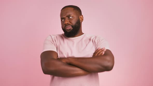 Offended African American Guy Folding Arms and Pouting Lips to Camera Pink Background