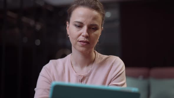 Portrait of Focused Caucasian Lady Scrolling Social Media or Shopping Online From Home Using Tablet