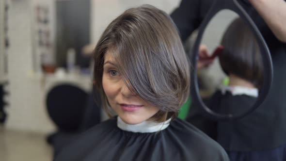 Professional Hairdresser Shows Short Haircut with Mirror to Handsome Satisfied Female Client in