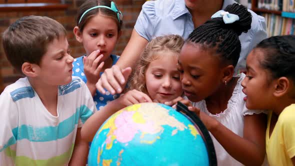 Pupils Looking at the Globe in Library with their Teacher