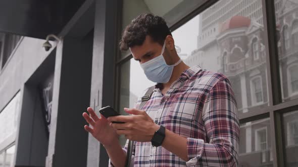 Low angle view of Caucasian man using his phone and wearing coronavirus covid19 mask