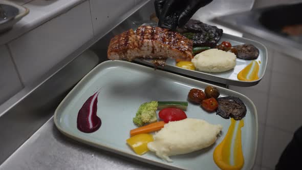 Serving Portion of Grilled Salmon and Vegetables, Chef with Black Gloves