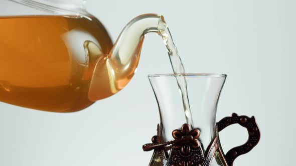 Pouring Citrus Black Tea in Armudu Glass on White Background