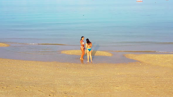 Sexy fun women on holiday enjoying life at the beach on sunny blue and white sand 4K background