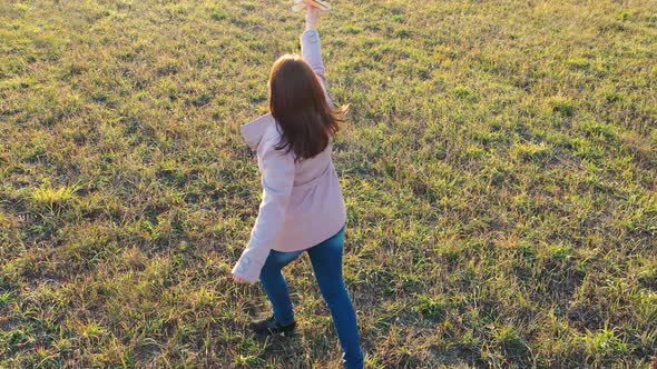 The Girl Runs Across the Field Holding a Plane Simulates Flight