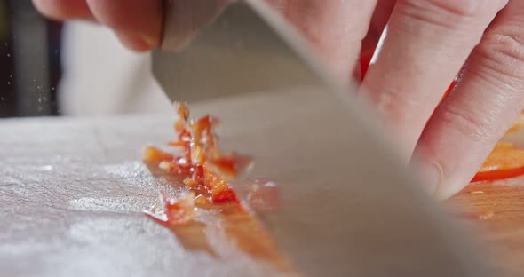 Extreme macro of a chef knife slicing a red bell pepper