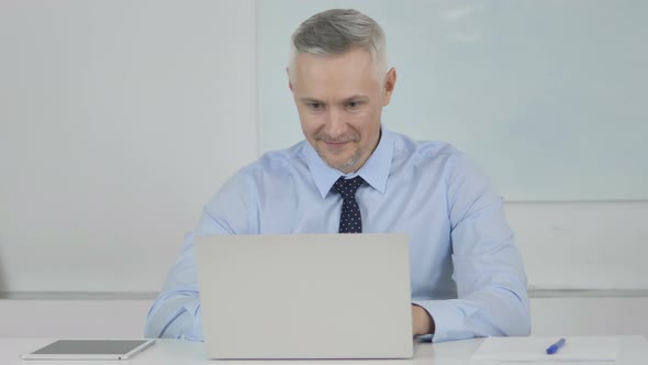 Excited Senior Businessman Celebrating Success While Working on Laptop