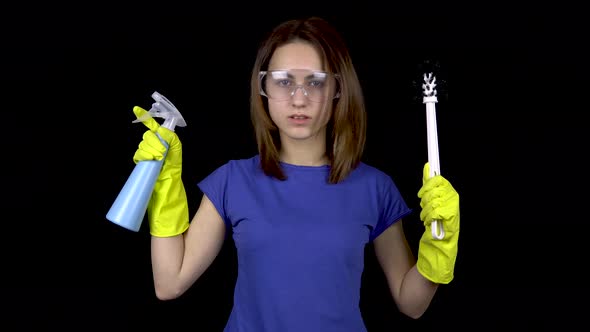 A Young Woman Shoots From a Water Spray Like a Pistol. Woman in Safety Glasses and Gloves with Tools