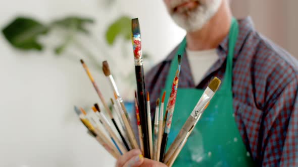 Man Artist Holds Lot of Brushes in Hands  Closeup