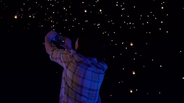 Asian woman watches as sky lanterns fly Into the night sky