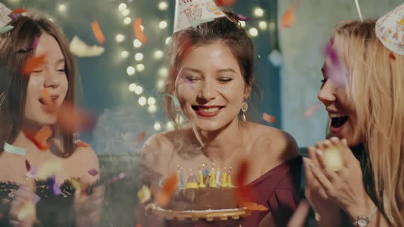 Portrait of Attractive Asian Girl Blowing Out Fire Candles on Birthday Cake Under Falling Glowing