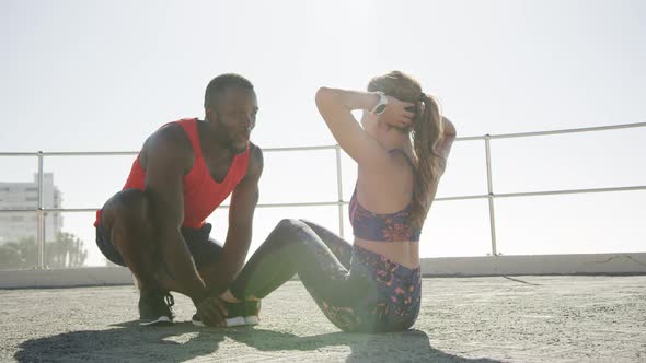 Man helping woman to perform abdominal exercise on a promenade 4k