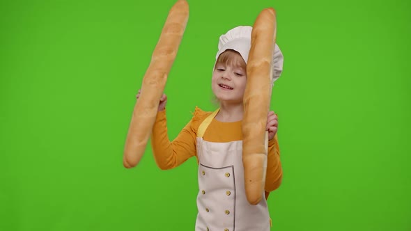 Child Girl Cook Chef Baker in Apron and Hat Sniffing Two Baguettes Fooling Around Dancing