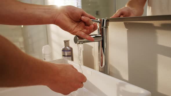 Man washing his hands in bathroom sink