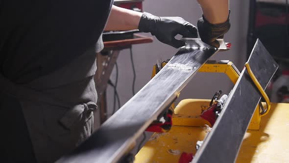 Ski Maintenance and Repair Concept. Workshop Worker Doing Waxing and Repairs Ski and Snowboard