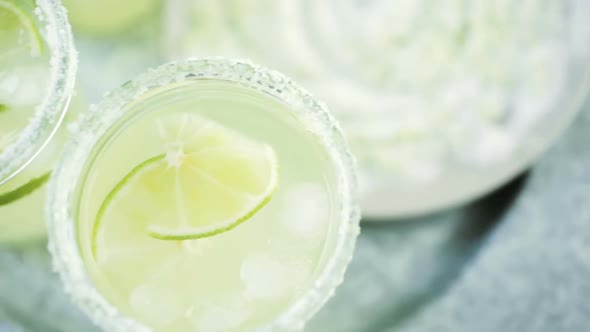 Key lime margarita garnished with fresh lime and salt in mason jar on metal tray.
