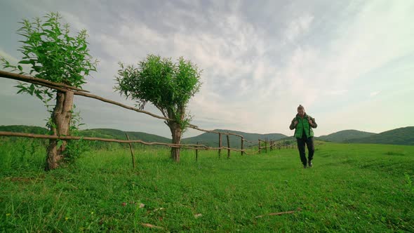 A Tourist with a Backpack Walks Along the Pathin the Background of the Mountain