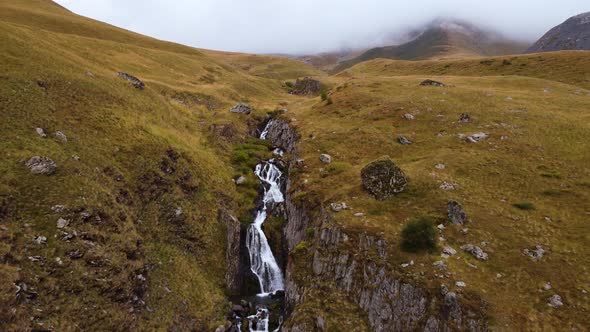 Waterfall in the autumn foggy mountains