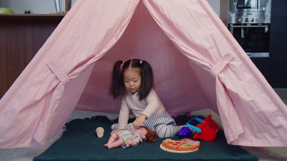 Positive Asian Toddler Girl Playing with Toys in Kids Tent