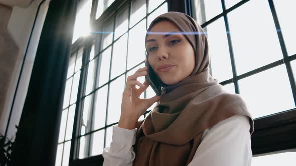 Young Muslim Girl Talking on the Phone in Bright Sunny Studio
