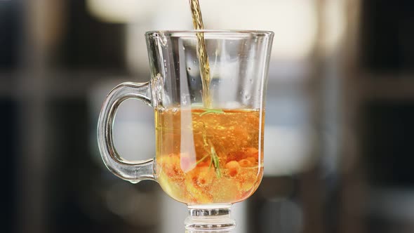 Close Up Pouring Fresh Appetizing Tea with Herb and Berry in Glass Cup