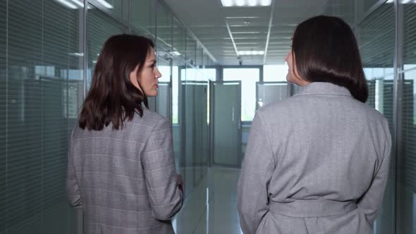 Lady Manager and Director Walk Along Dark Office Hallway